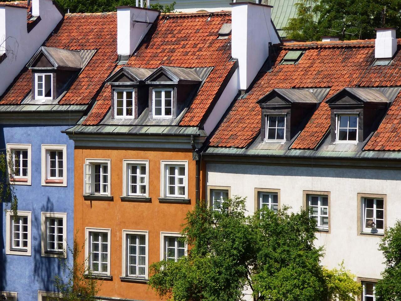 A row of townhouses with red tile pitched roofs and dormer windows